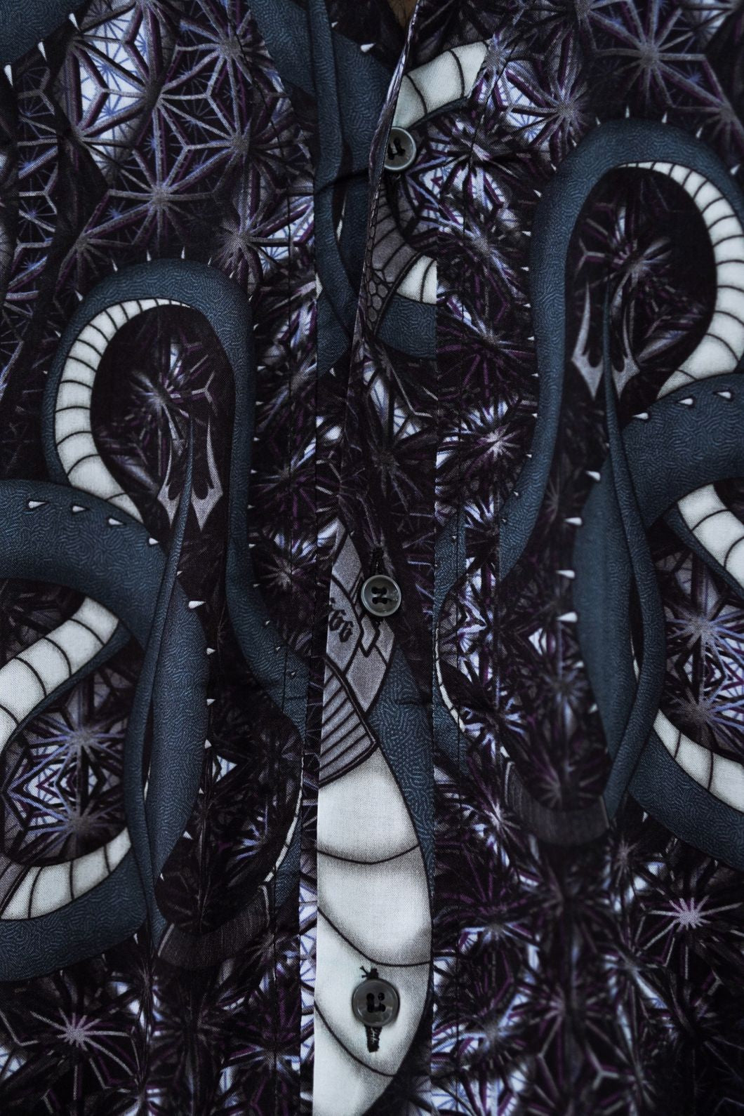 Close-up of bamboo sleeveless shirt showing psychedelic digital print, button-down details, and lightweight fabric texture
